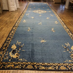 Long runner rug in blue with a geometric field and detailed yellow and black patterned borders on a wood floor.