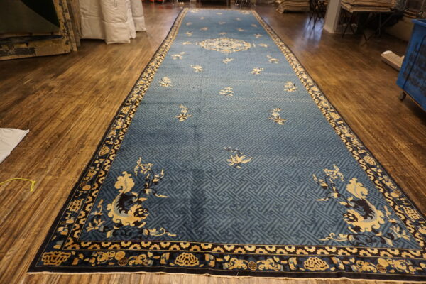 Long runner rug in blue with a geometric field and detailed yellow and black patterned borders on a wood floor.