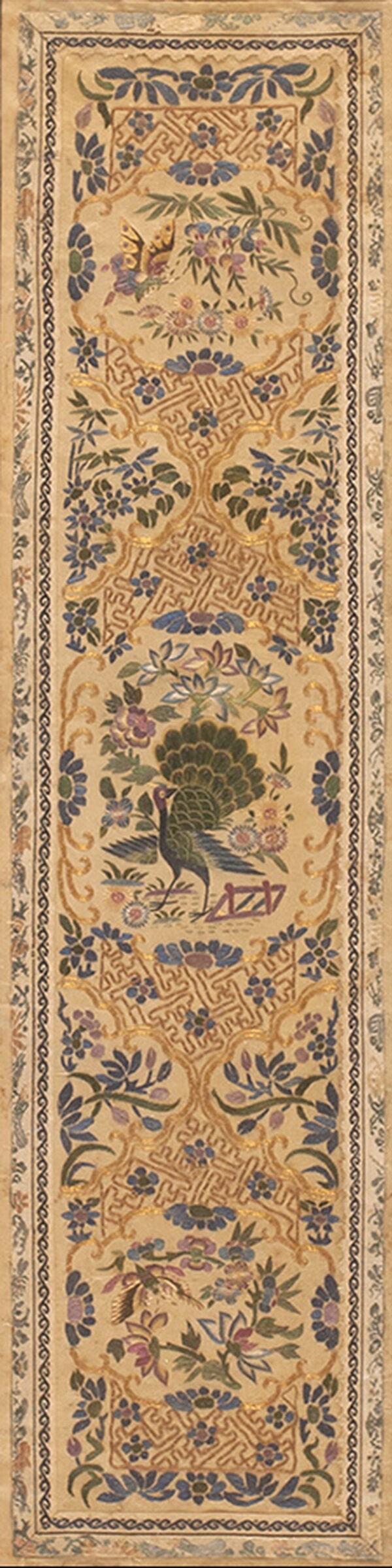 Vertical beige textile panel displaying a peacock, butterfly, blue flowers, and intertwining geometric gold lines.