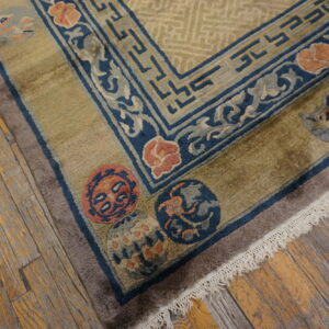 Geometric and floral patterned rug corner showing olive green, navy, and peach colors on rustic wood planks.