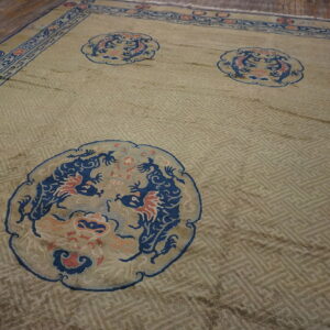Pale green rug with a fretwork background and three blue dragon medallions, resting on wood planks.