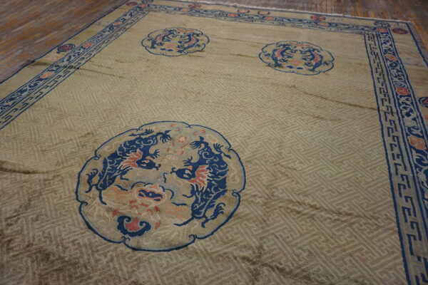 Pale green rug with a fretwork background and three blue dragon medallions, resting on wood planks.