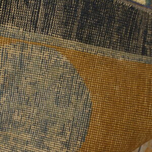 Close-up of a rug's tightly woven backing and colorful design in navy, gold, and pale blue.