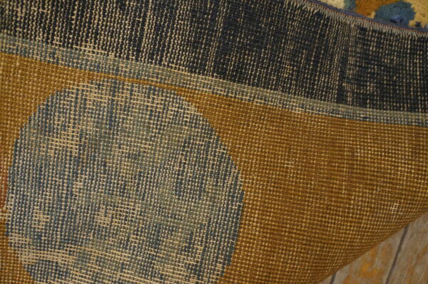 Close-up of a rug's tightly woven backing and colorful design in navy, gold, and pale blue.
