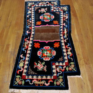 Black runner rug with vibrant traditional patterns and a brown textured band centered on wood floors.