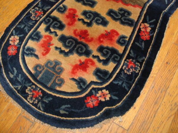 Contoured tan rug featuring red and dark blue patterns, bordered by florals, resting on hardwood plank flooring.
