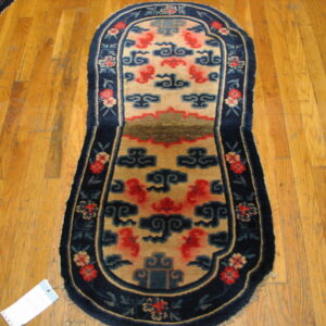 Red and blue cloud motifs adorn this long, shaped tan rug placed upon glossy hardwood planks.