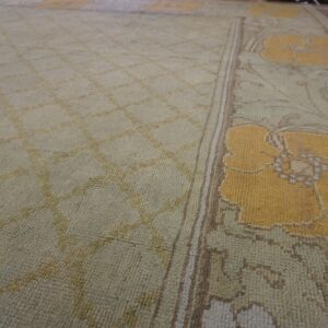 Pale green low-pile rug with a diamond field transitioning to a border of large yellow floral motifs.