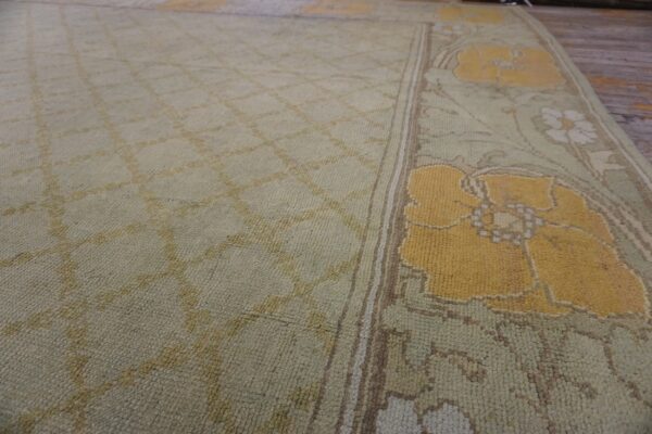 Pale green low-pile rug with a diamond field transitioning to a border of large yellow floral motifs.