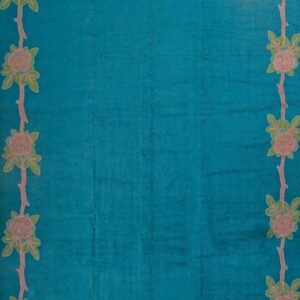 Turquoise rug with floral border design.