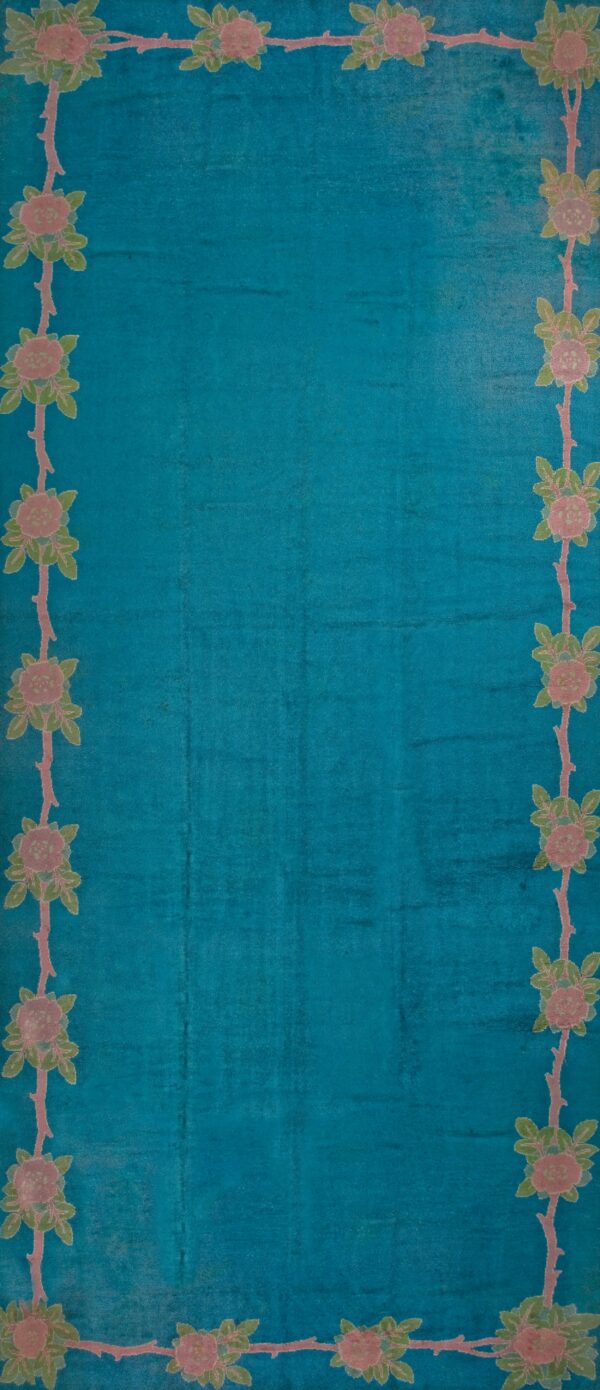 Turquoise rug with floral border design.