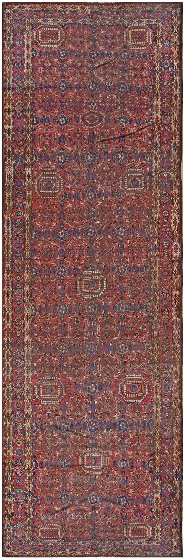 Red runner rug with an all-over navy blue and cream geometric pattern and wide decorative border.