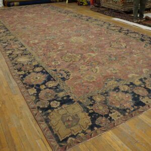 Long, worn rug featuring red, yellow, and navy floral motifs rests on hardwood flooring.