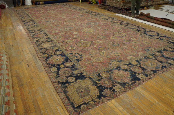 Long, worn rug featuring red, yellow, and navy floral motifs rests on hardwood flooring.
