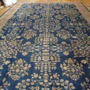 Long deep blue rug featuring an intricate floral pattern and a rust-toned border on wood flooring.