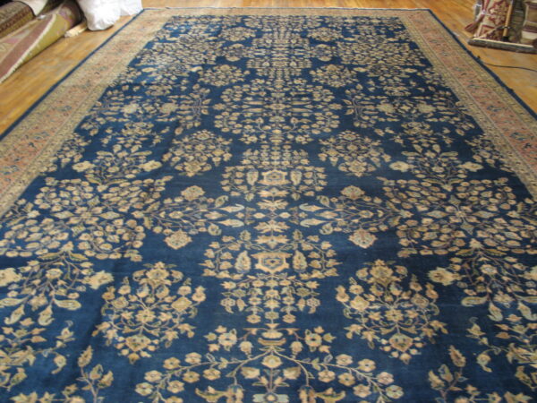Long deep blue rug featuring an intricate floral pattern and a rust-toned border on wood flooring.