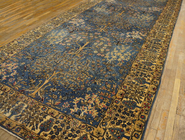 Long blue rug with golden botanical tree of life design displayed on a distressed wooden floor.