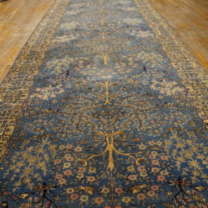 Intricate blue runner rug with a yellow tree-of-life and floral motif resting on worn wood flooring.
