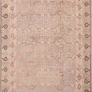 A faded pink and pale blue rug with a dense geometric pattern and multiple ornate borders.