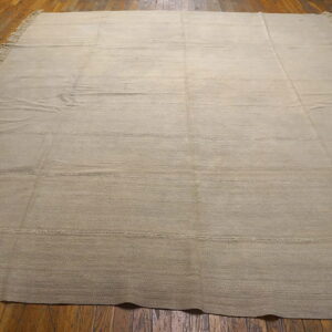 Neutral tan flatweave rug featuring subtle horizontal stitched lines on dark hardwood floors.