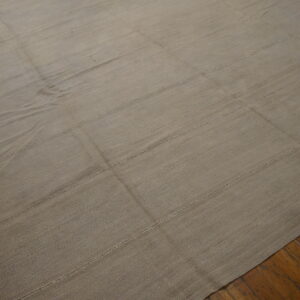 Taupe flatweave rug with horizontal seams and fringe displayed on distressed wood planks.