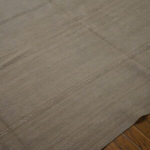A textured taupe flatweave rug with horizontal seams rests on dark hardwood floors.