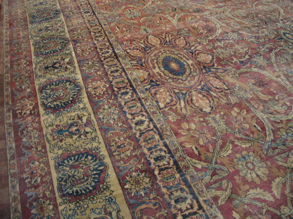 A detailed rug featuring red, cream, and blue traditional floral patterns and distinct borders.