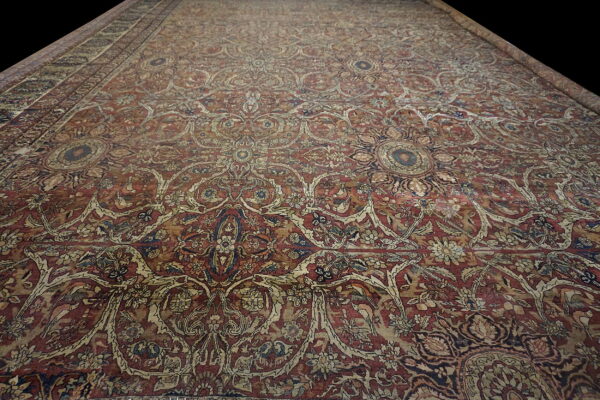 Ornate red and tan rug with a low pile featuring intricate floral medallions on a dark background.