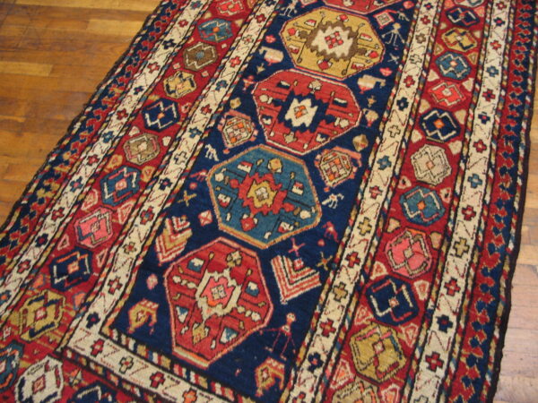 Navy blue and red geometric rug featuring octagonal medallions rests on polished wood floorboards.