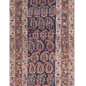 Low-pile navy blue runner with repeating rust and gold traditional paisley motifs and complex borders.