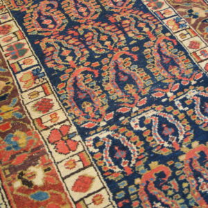 Traditional rug with a navy blue field, ornate paisley and floral patterns, and multi-colored guard borders.