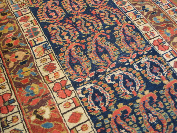 Traditional rug with a navy blue field, ornate paisley and floral patterns, and multi-colored guard borders.