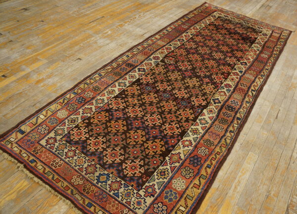 Long dark geometric runner rug with red and blue accents on distressed wood flooring.