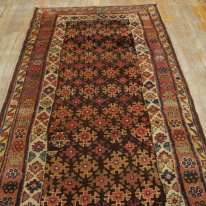 Geometric runner rug with dark brown, red, and beige colors on rustic, worn wood flooring.