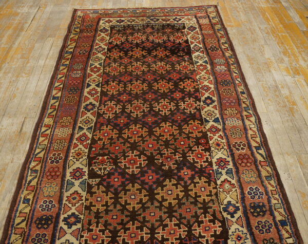 Geometric runner rug with dark brown, red, and beige colors on rustic, worn wood flooring.