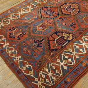 Geometric red, blue, and cream tribal rug with low pile placed on rustic wooden flooring.