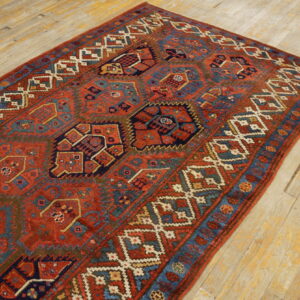 Red and blue tribal-style rug with complex geometric medallions on distressed blonde hardwood flooring.