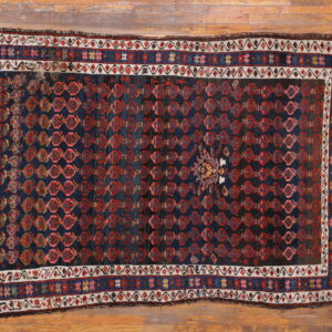 Dark blue rug featuring repeated red diamond motifs and a central medallion on natural wood floor.