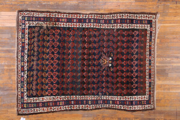 Dark blue rug featuring repeated red diamond motifs and a central medallion on natural wood floor.