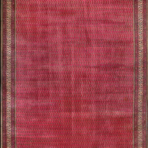 Deep red rug featuring a dense paisley field pattern surrounded by an elaborate gold and maroon border.