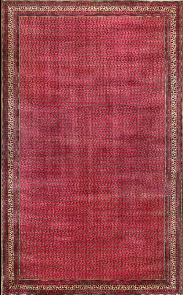 Deep red rug featuring a dense paisley field pattern surrounded by an elaborate gold and maroon border.