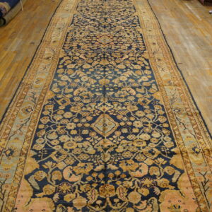 Navy runner with detailed gold and pink floral patterns covers aged yellow hardwood flooring.