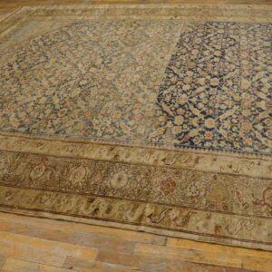 Large blue and beige patterned rug shows strong color contrast across its worn floral field on hardwood.