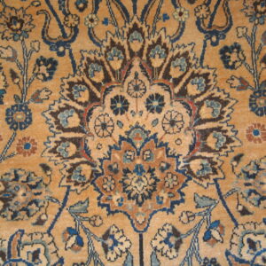 Detailed low-pile rug section showing a complex medallion pattern in navy, rust, and brown on a tan field.