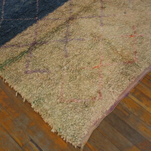 Diagonal color-block shaggy rug in cream and navy blue with geometric patterns on brown wood flooring.