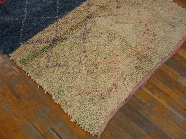 Diagonal color-block shaggy rug in cream and navy blue with geometric patterns on brown wood flooring.