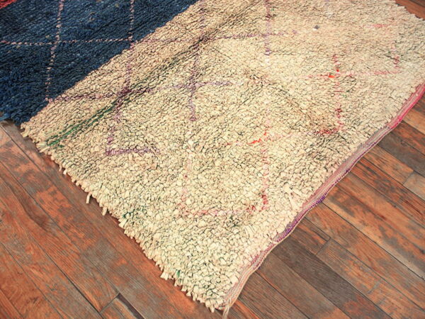 High-pile shag rug split between dark blue and off-white sections rests on a brown plank floor.