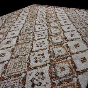 High-pile rug with a repeating diamond pattern in off-white, brown, and bright orange colors.