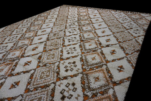 High-pile rug with a repeating diamond pattern in off-white, brown, and bright orange colors.