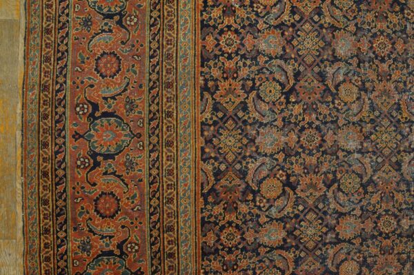 Intricate traditional rug with a rust border and navy central field showing distressed gold and teal patterns.